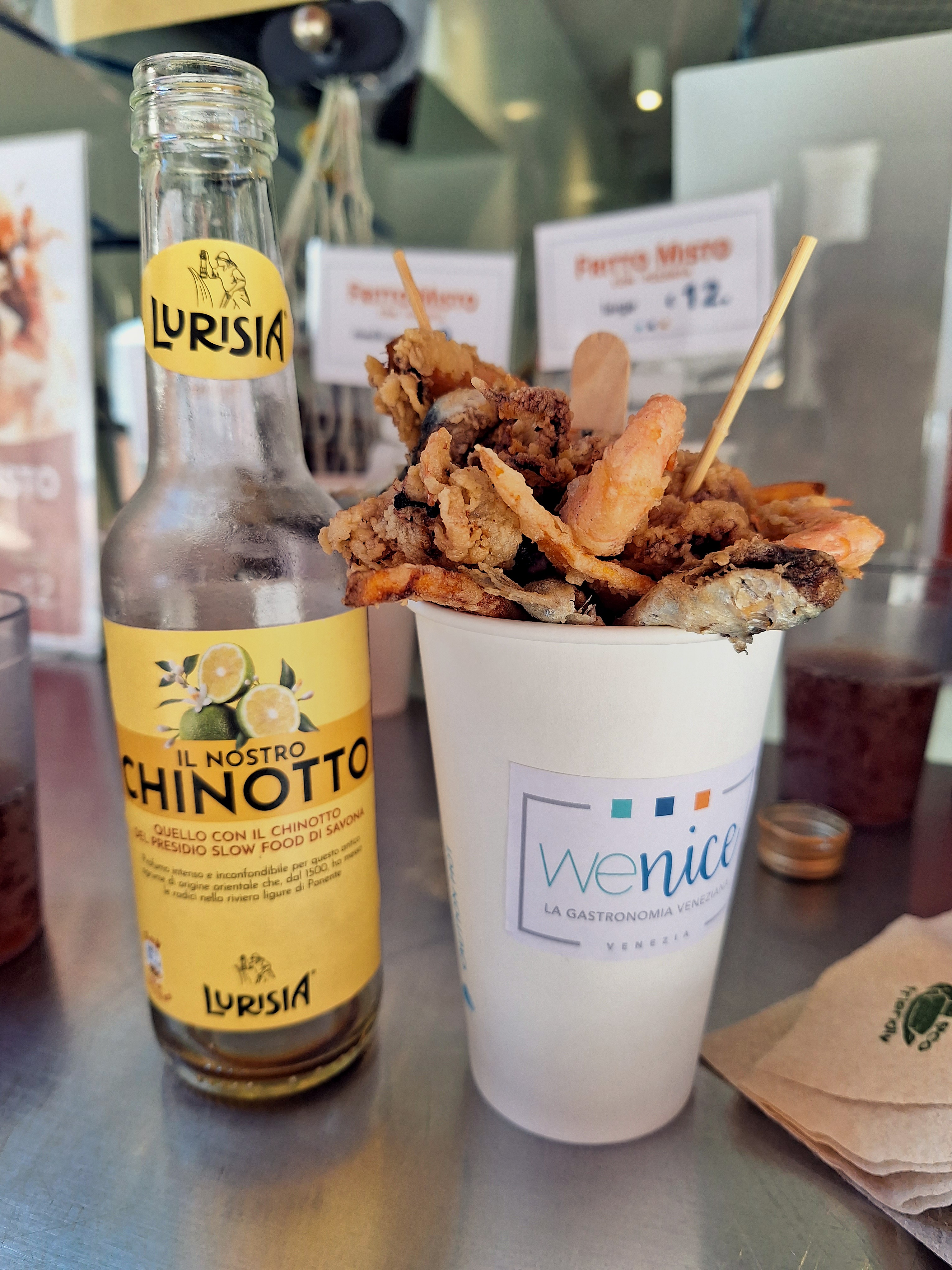Fritto misto in a paper cup from We Nice with a bottle of Chinotto Lurisia