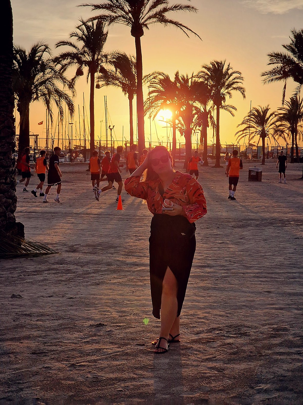Palm trees, a beach volleyball game, and a warm sun setting behind the Palma marina