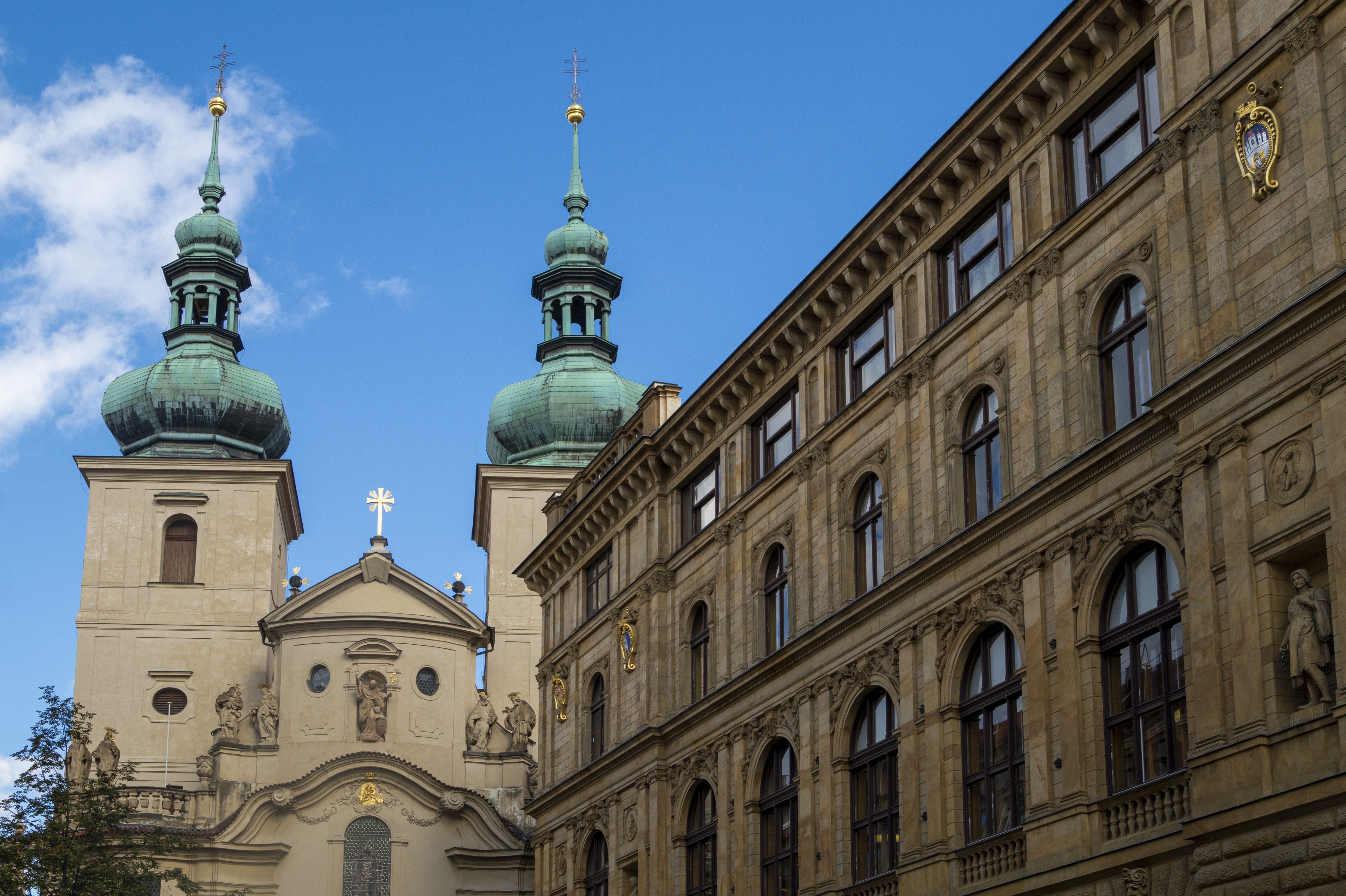 The twin green-domed onion towers of the baroque Church of St Gallus in Prague, with neighbouring honey-coloured neo-renaissance buildings