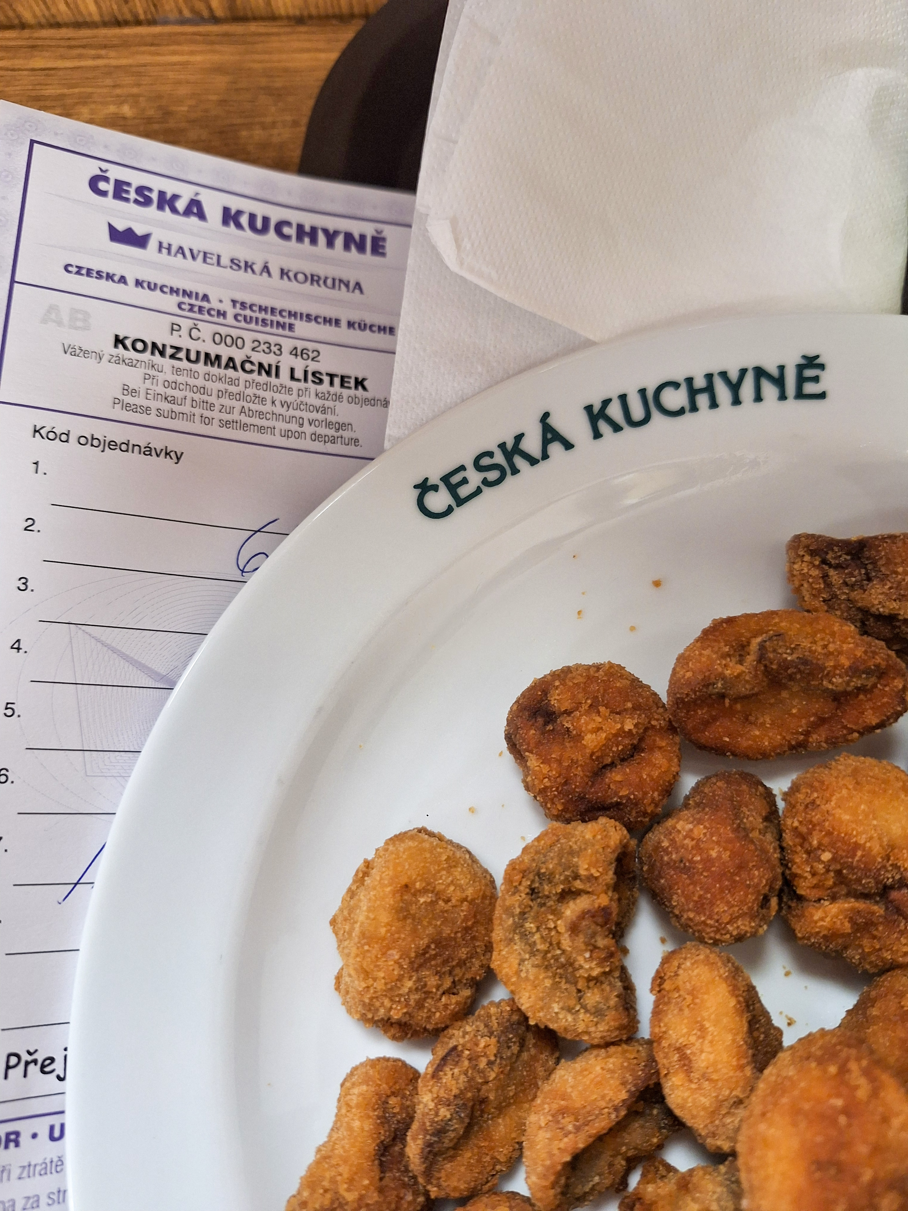 A plate of golden breaded fried Czech cheese — smažený sýr — at Česká Kuchyně Havelská Koruna restaurant in Prague, with a paper menu card on the side