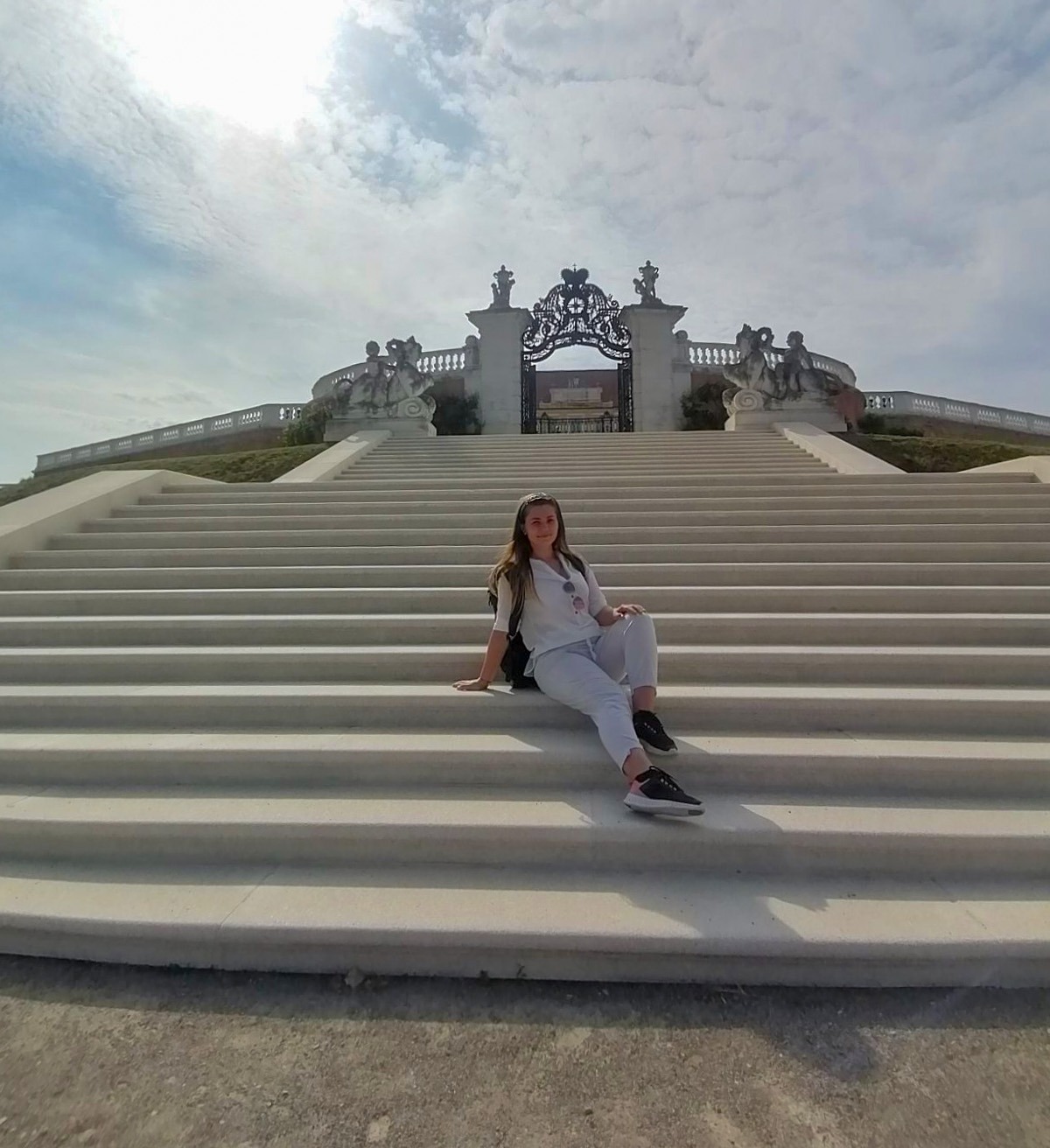 The grand white stairs of Schloss Hof with a wrought-iron gate crowned by the imperial Habsburg crown at the top