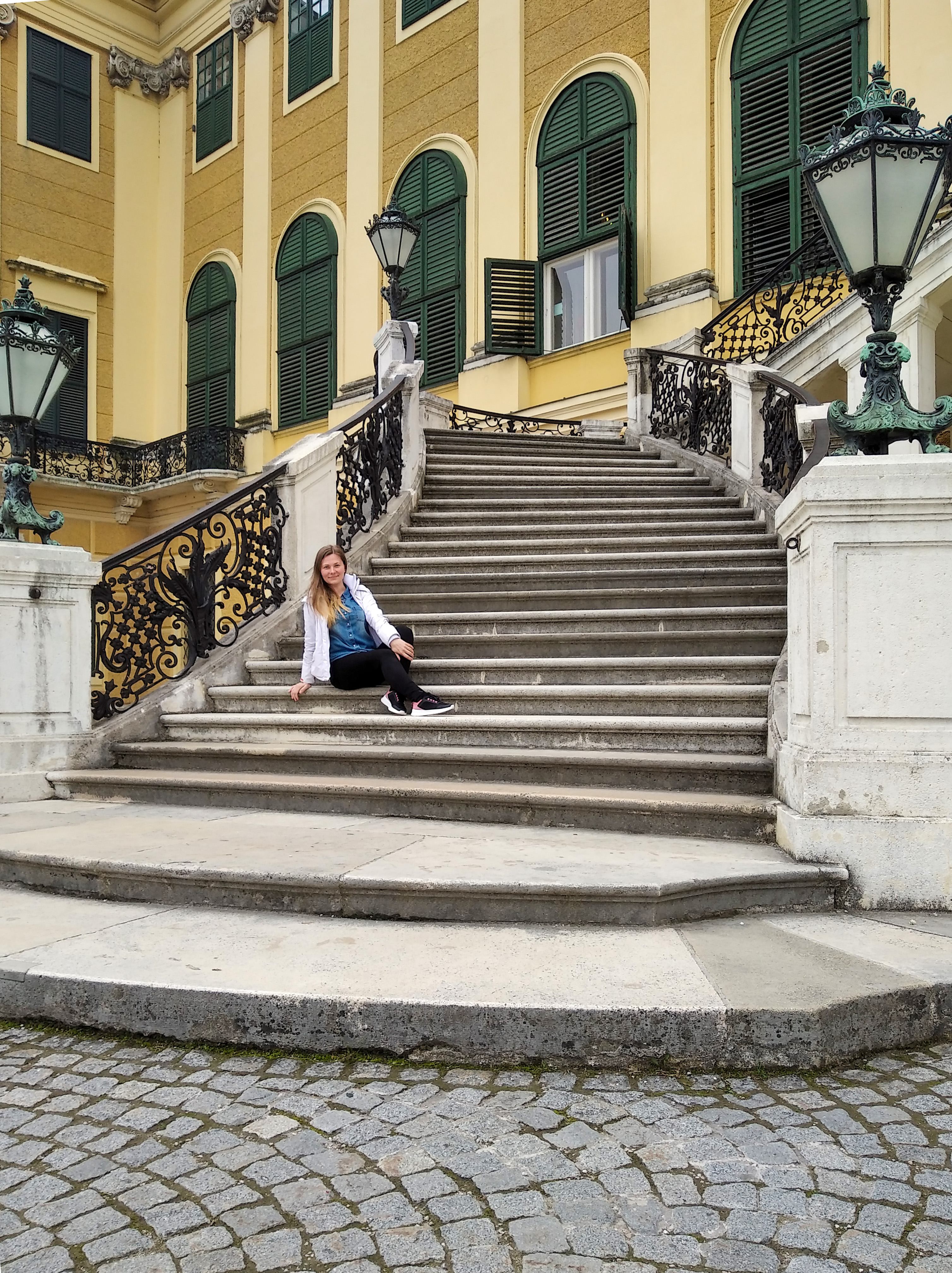 Side staircase of Schloss Schönbrunn with gilded wrought-iron railings and the yellow Habsburg façade behind